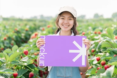American Woman Holding Poster Mockup in Strawberry Field