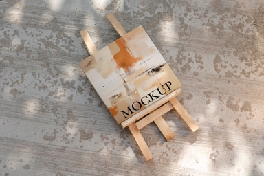 Square Canvas Mockup with Easel Laying on Cemented Road