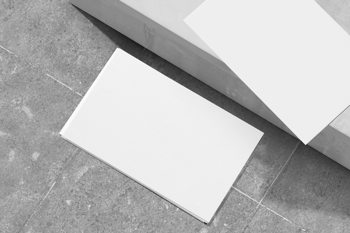 Two white business cards with a geometric pattern mockup on concrete