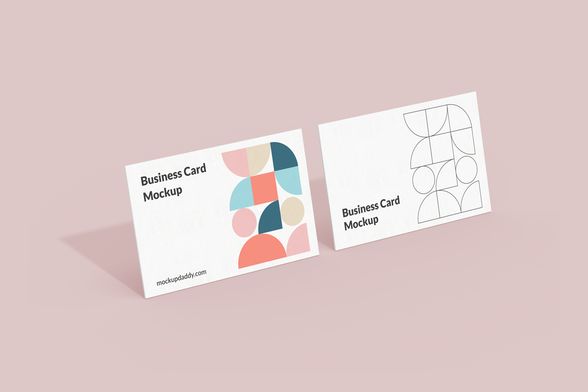 Two business cards sitting side-by-side on a pink surface.