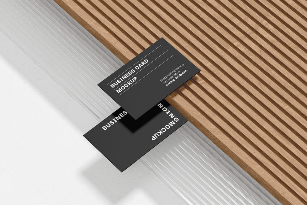 Two business cards, side-by-side, on a wooden table.